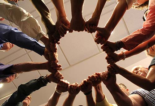 Group of people with their fists clasped making a circle - Well of Confidentiality - Action Intervention Training in Savannah - Personal Growth Training for Professionals at Action Institute of California