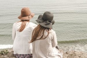 two women sitting on a beach looking out at the ocean - doubling as co-regulation - jean campbell - action institute of california - psychodrama training institute in san diego california