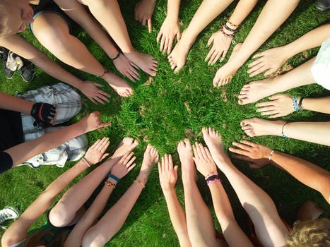 hands and feet in a motivational circle in the grass