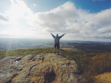 Person standing at the top of a mountain with their arms out - victory